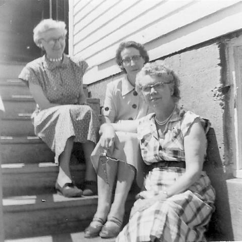 Three West Lakeside School teachers. They are sitting on the back steps of the school. Mrs. Jingle, Mrs. Knudson, and Mrs. Ruth Kline.